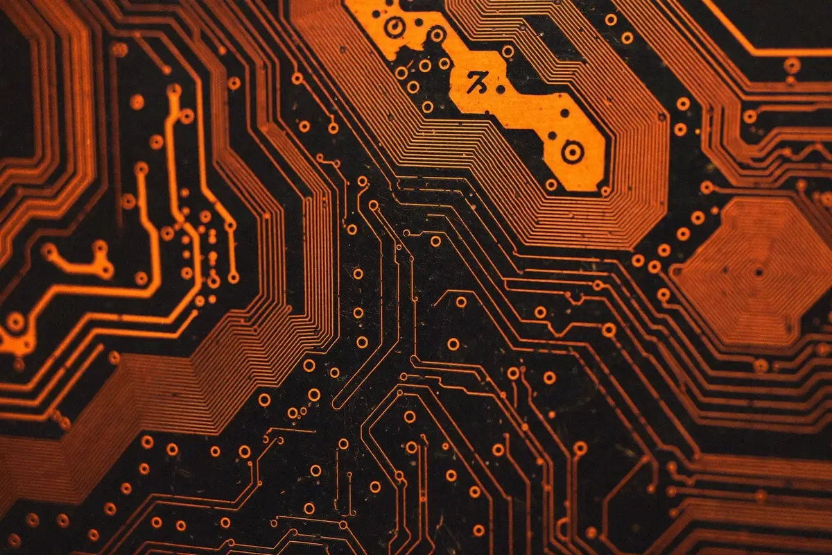 Abstract macro of circuit-board traces glowing ember orange on a dark substrate
